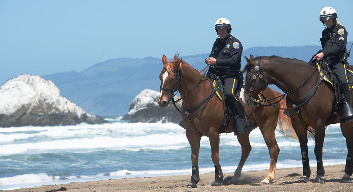 Image of two mounted police officers at a beach